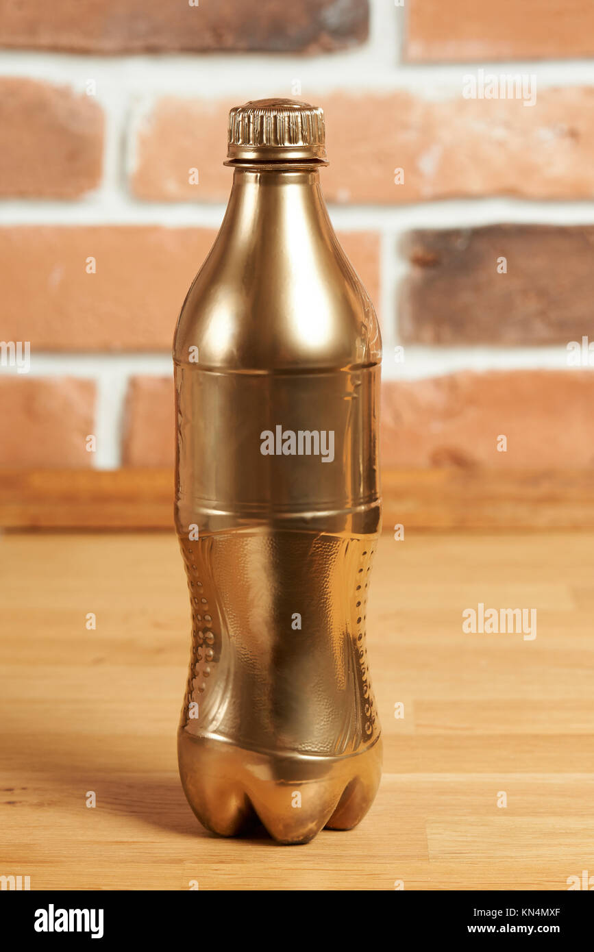 One plastic golden bottle on wooden table. Luxury drink concept Stock Photo