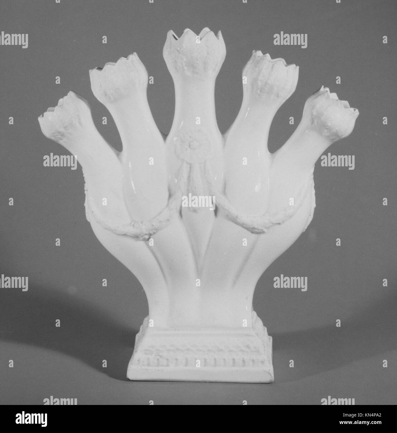 This finger vase, a distinct piece in ceramic art, features a narrow, elongated form with unique finger-like projections, which may represent naturalistic or abstract motifs. Its design demonstrates innovation in ceramic design. The vase is part of the MET's collection. Stock Photo
