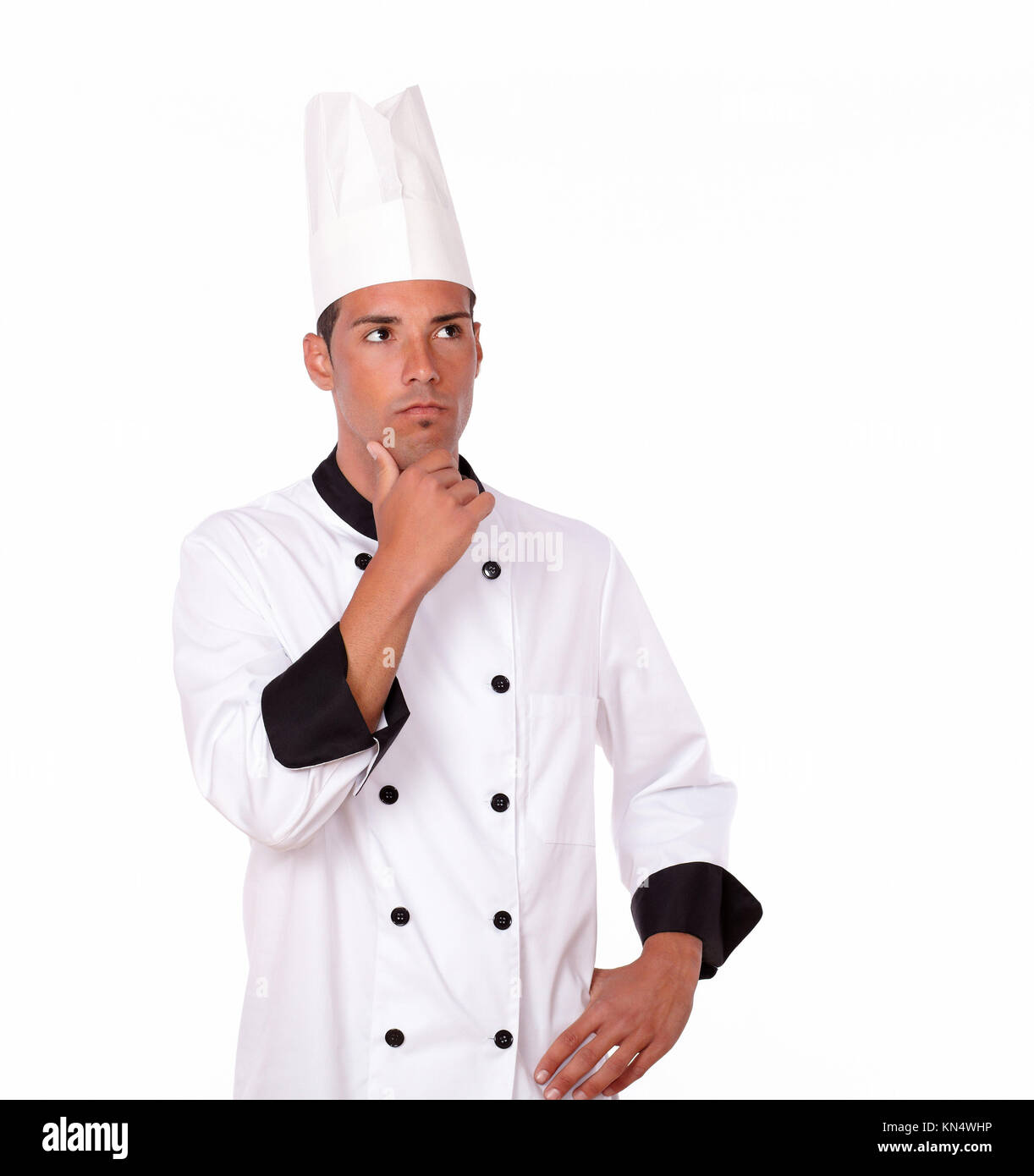 Portrait of pensive 20-24 years male chef on white uniform standing on isolated background - copyspace. Stock Photo