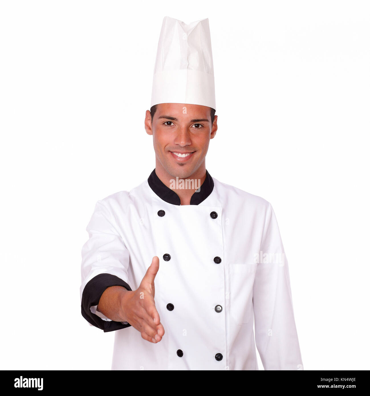 Portrait of handsome 20-24 years male chef on white uniform with greeting gesture smiling at you on isolated background. Stock Photo
