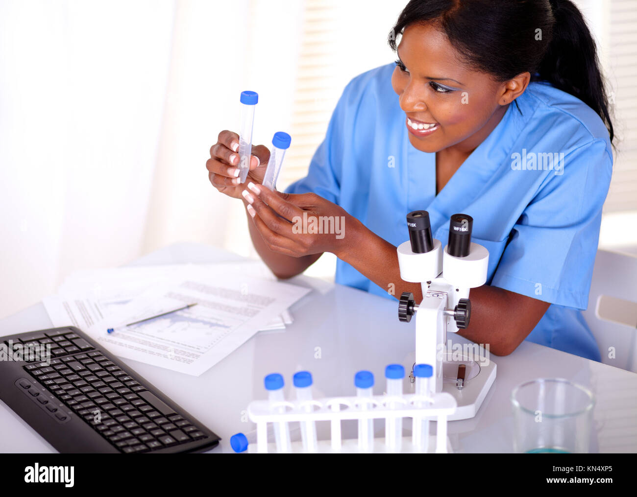 Satisfied scientific woman looking to test tube at laboratory. Stock Photo