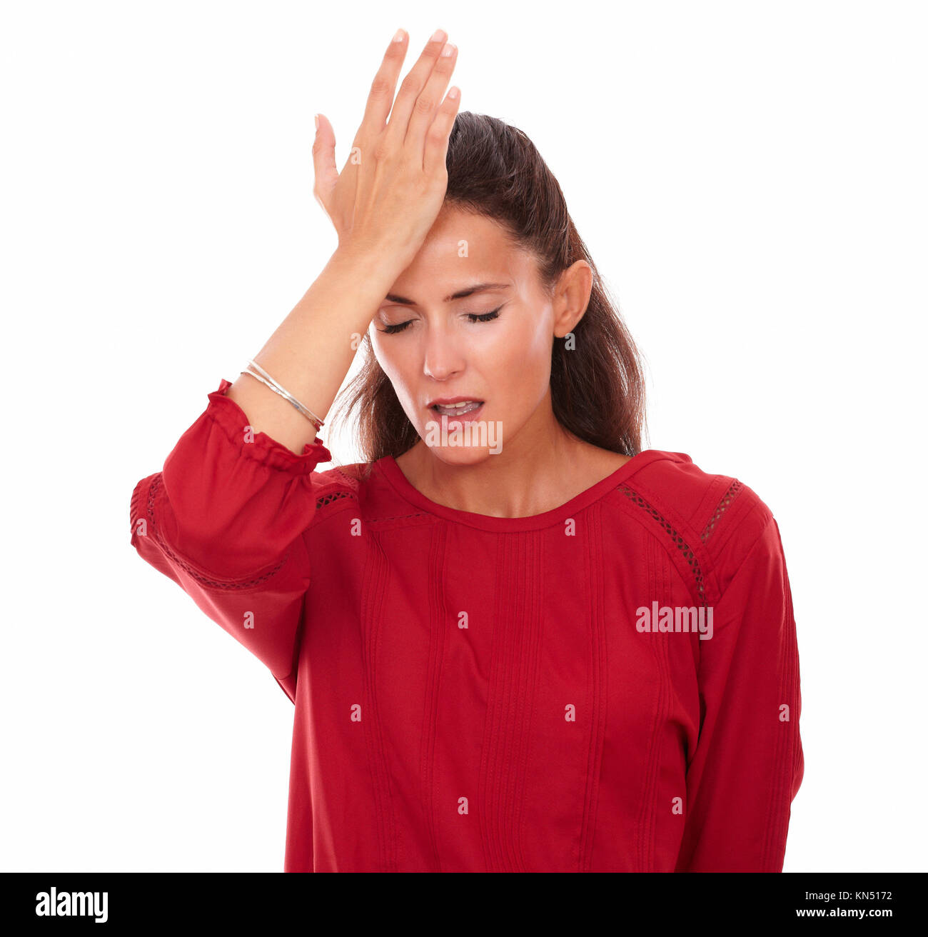 Portrait of single latin female on red blouse with head pain and closed eyes standing on isolated studio. Stock Photo