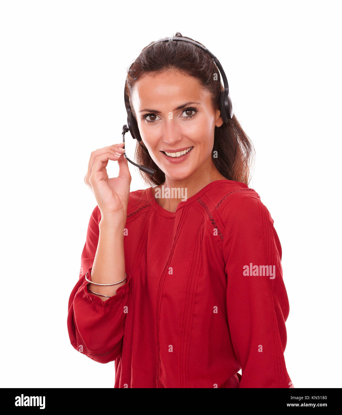 Portrait of lovely adult secretary speaking on headphones while smiling at you and standing on isolated studio. Stock Photo