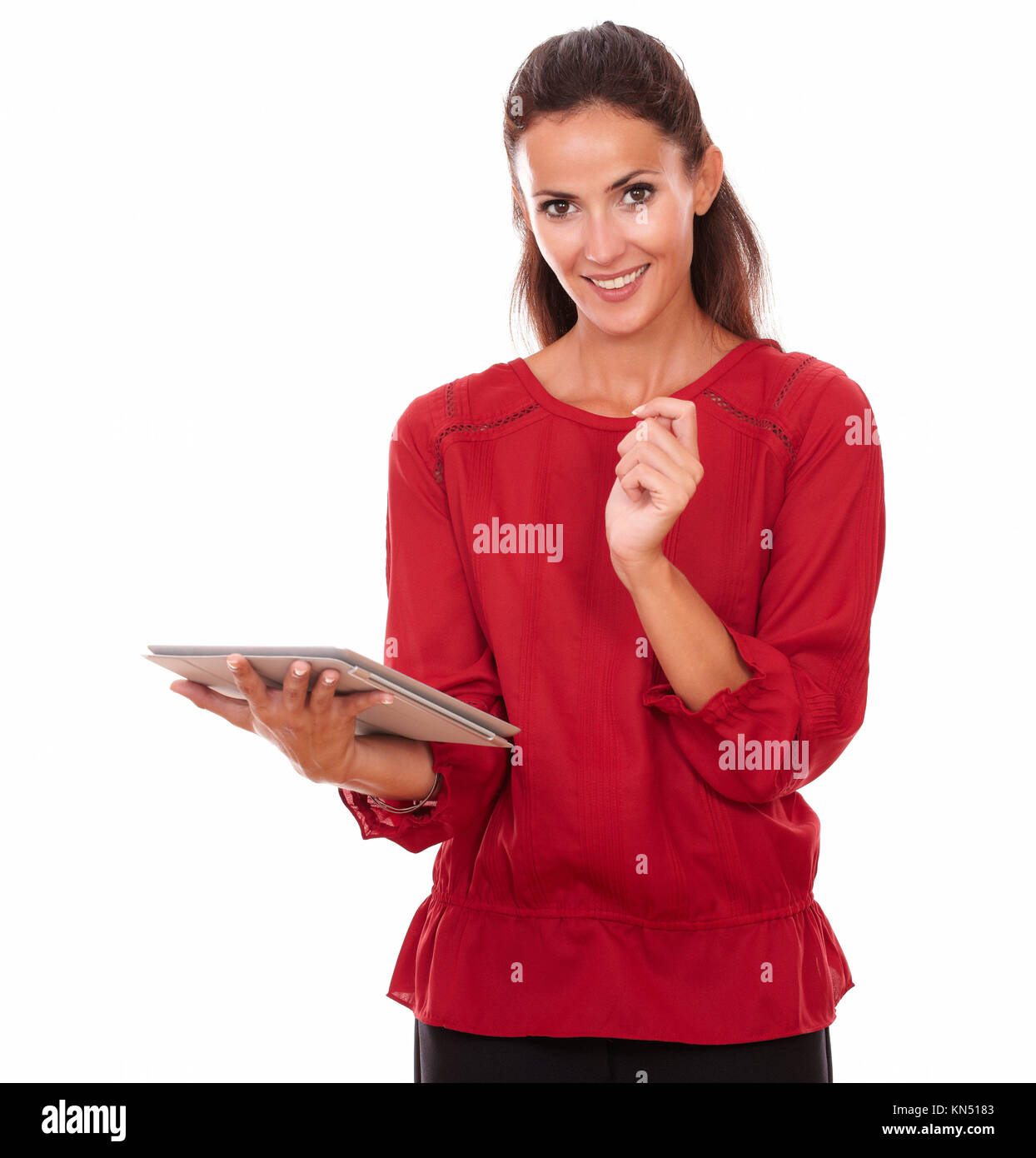 Portrait of pretty hispanic woman working on her tablet pc while standing and smiling at you on isolated studio. Stock Photo