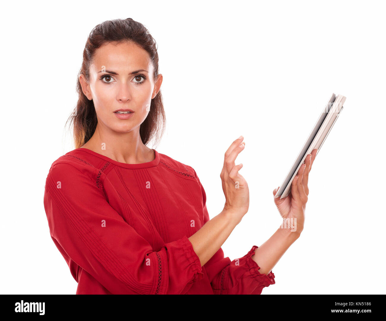 Portrait of surprised adult lady on red shirt working on her tablet pc looking at you on isolated studio. Stock Photo