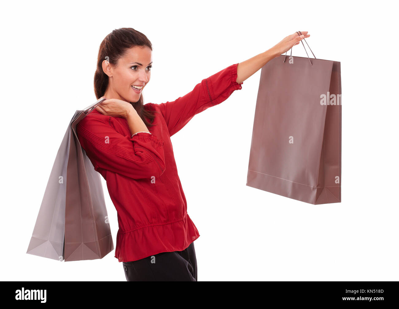 Portrait of stylish adult lady on red shirt with paper bag screaming while standing on isolated white background - copyspace. Stock Photo