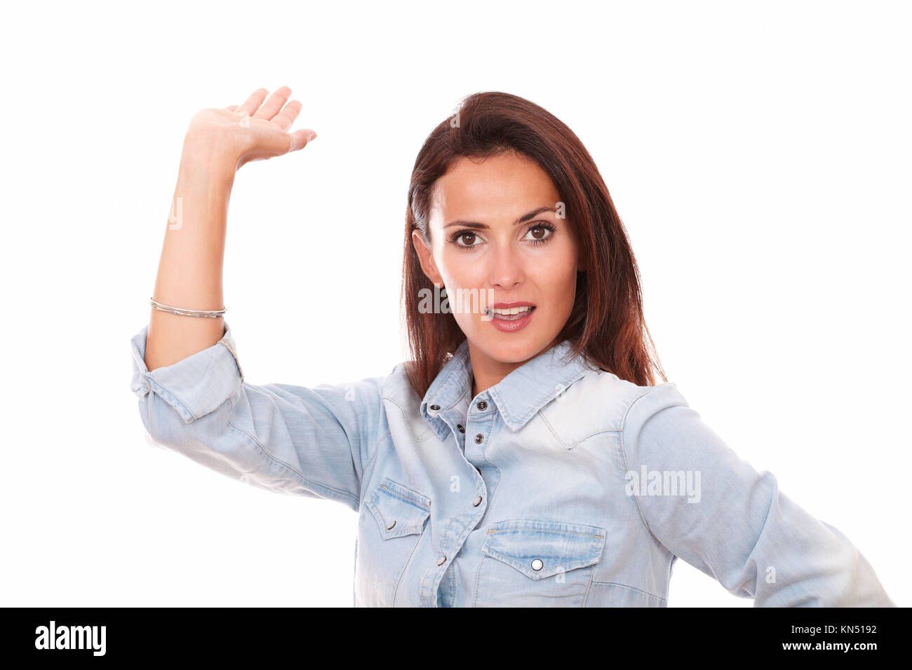 Portrait of pretty latin woman on blue blouse holding her right palm up while smiling at you on isolated white background - copyspace. Stock Photo