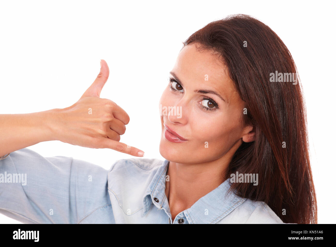 Closeup portrait of adult latin lady on blue shirt with call gesture smiling at you on isolated studio. Stock Photo