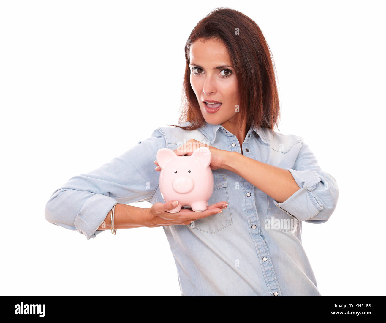 Portrait of attractive young lady on blue shirt with her piggybank smiling at you on isolated studio. Stock Photo