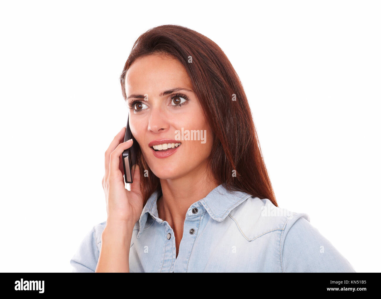 Portrait of pretty single lady on blue shirt speaking on her phone while smiling on isolated studio. Stock Photo
