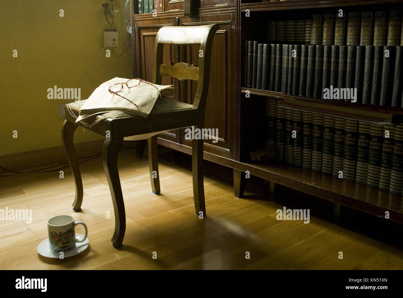 Reading room with chair, ancient open book with glasses and a cup
