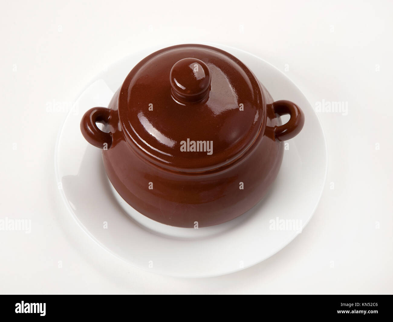 brown clay pot on a white plate the isolated Stock Photo - Alamy