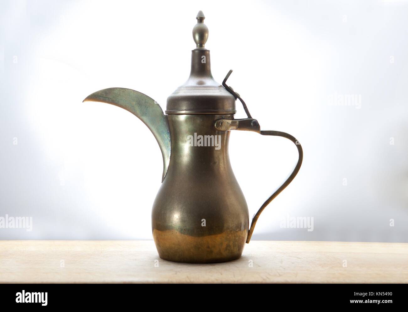 Old traditional arabic pitcher isolated over white background, placed on wooden surface. Stock Photo