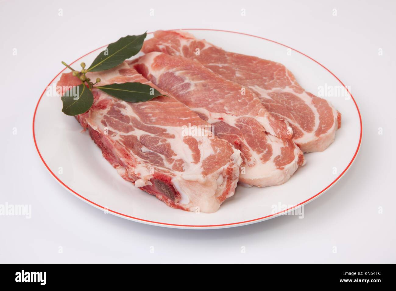 Middle rib chops of pork over plate. Isolated on white with bay. Stock Photo