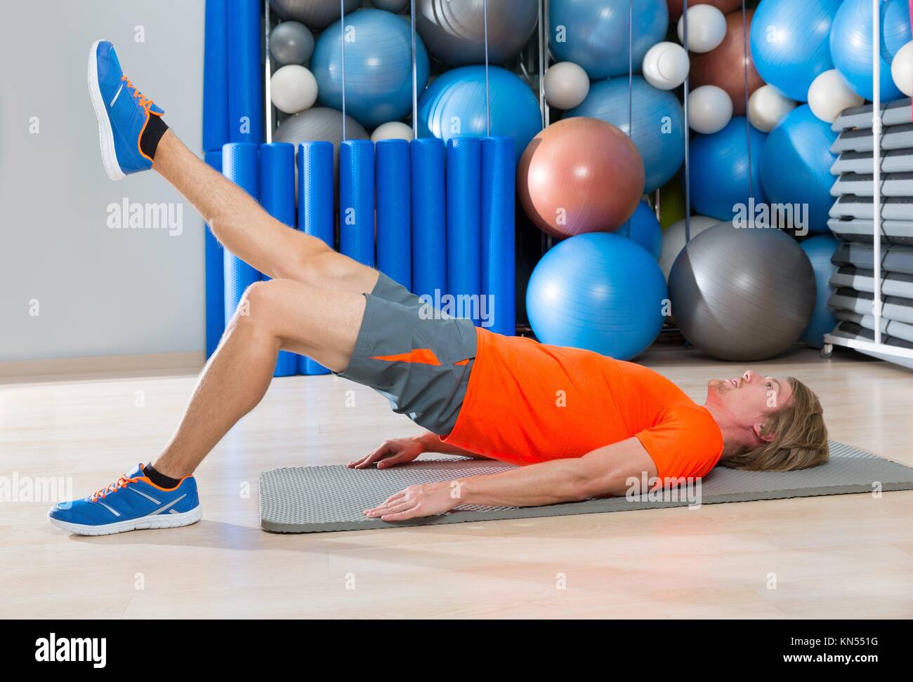 hip lift with leg extension blond man at gym workout with swiss ball