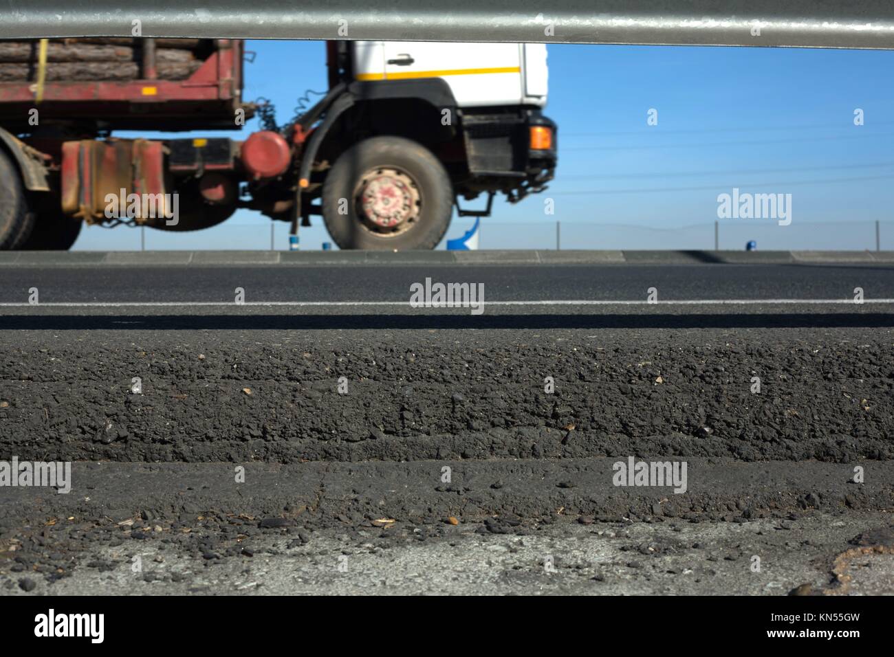 Truck wheels between dark asphalt road and rail guards. Motion shot. Stock Photo