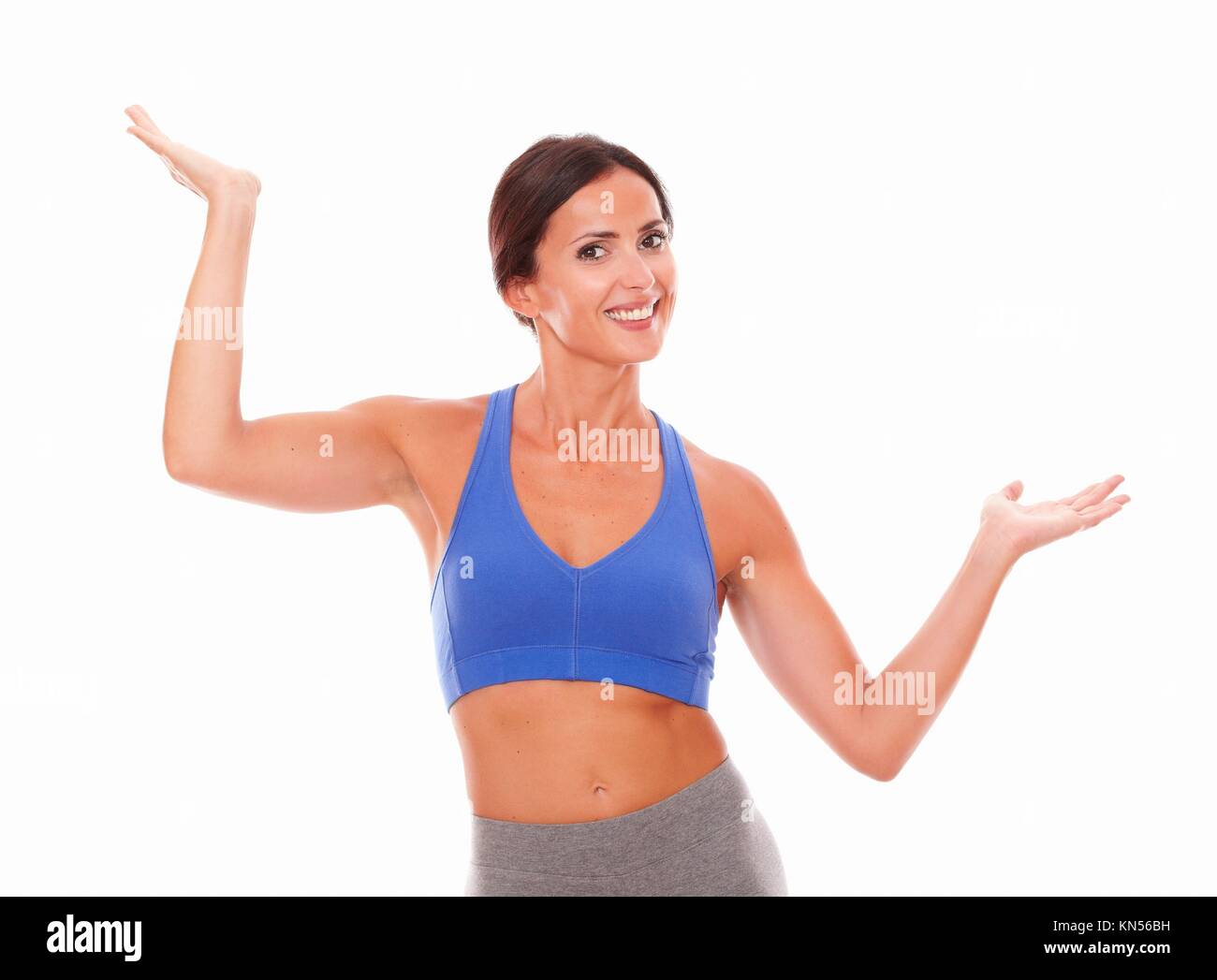 Beautiful hispanic lady in sportswear putting hands up while looking at you against white background - copyspace. Stock Photo