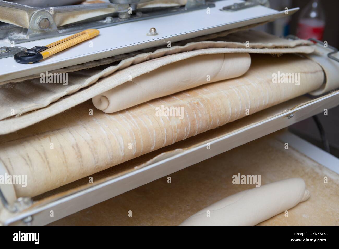 Dough divider and moulder machine at work. Manufacturing process of spanish bread. Stock Photo