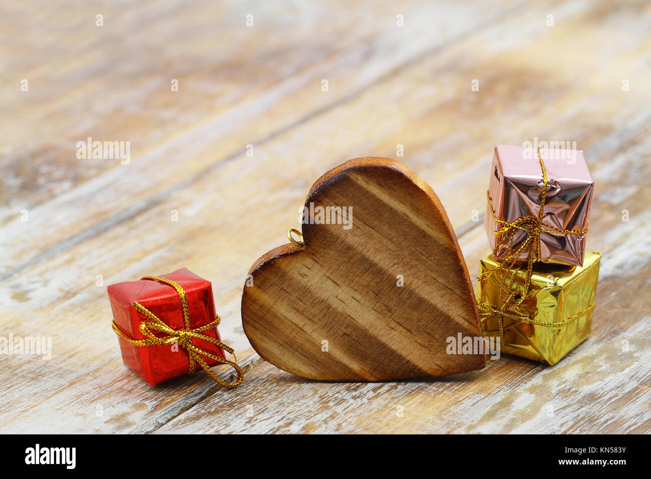 Wooden heart and shiny Christmas gifts on wooden surface with copy space Stock Photo