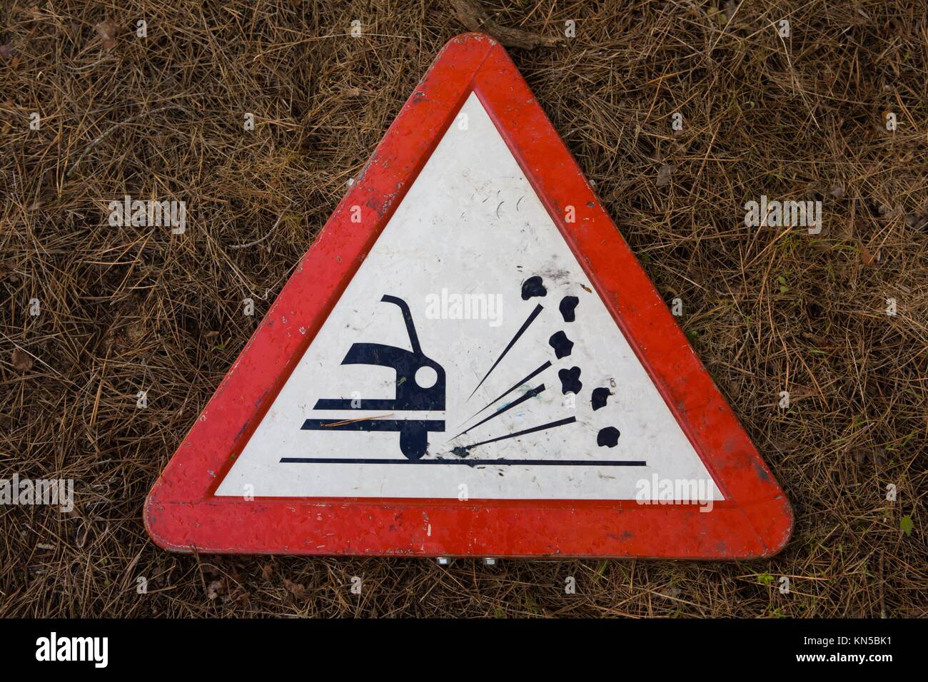 triangle traffic sign for gravel isolated over dry grassy background. Stock Photo