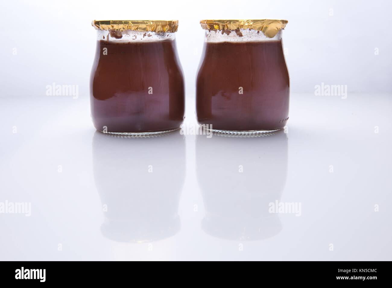 Chocolate truffle glass vessels with golden cap over white background. Stock Photo