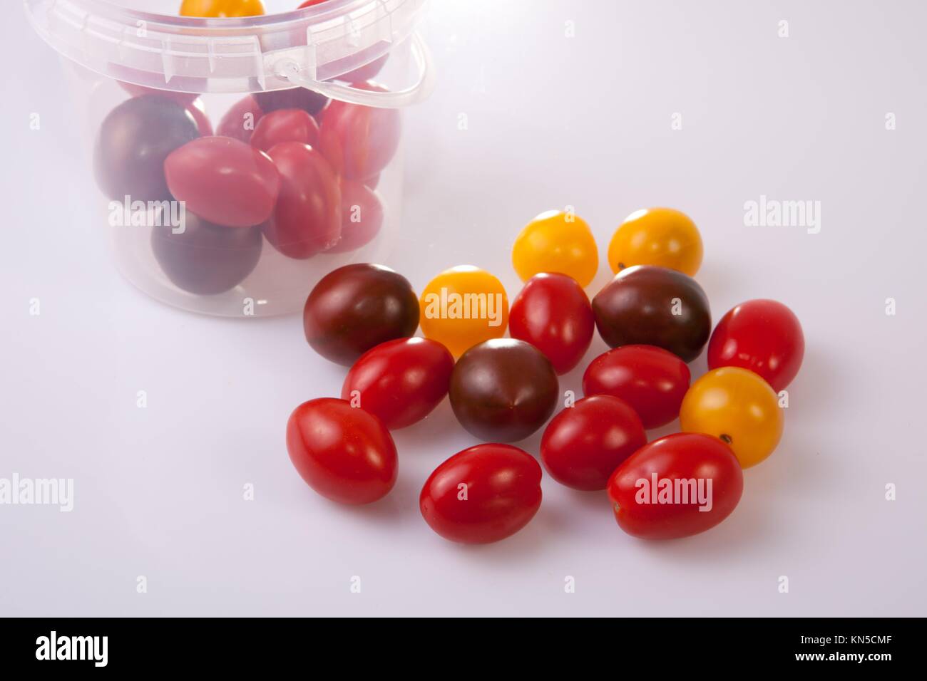 Bucket and colorful cherry tomatoes. Isolated over white background. Stock Photo