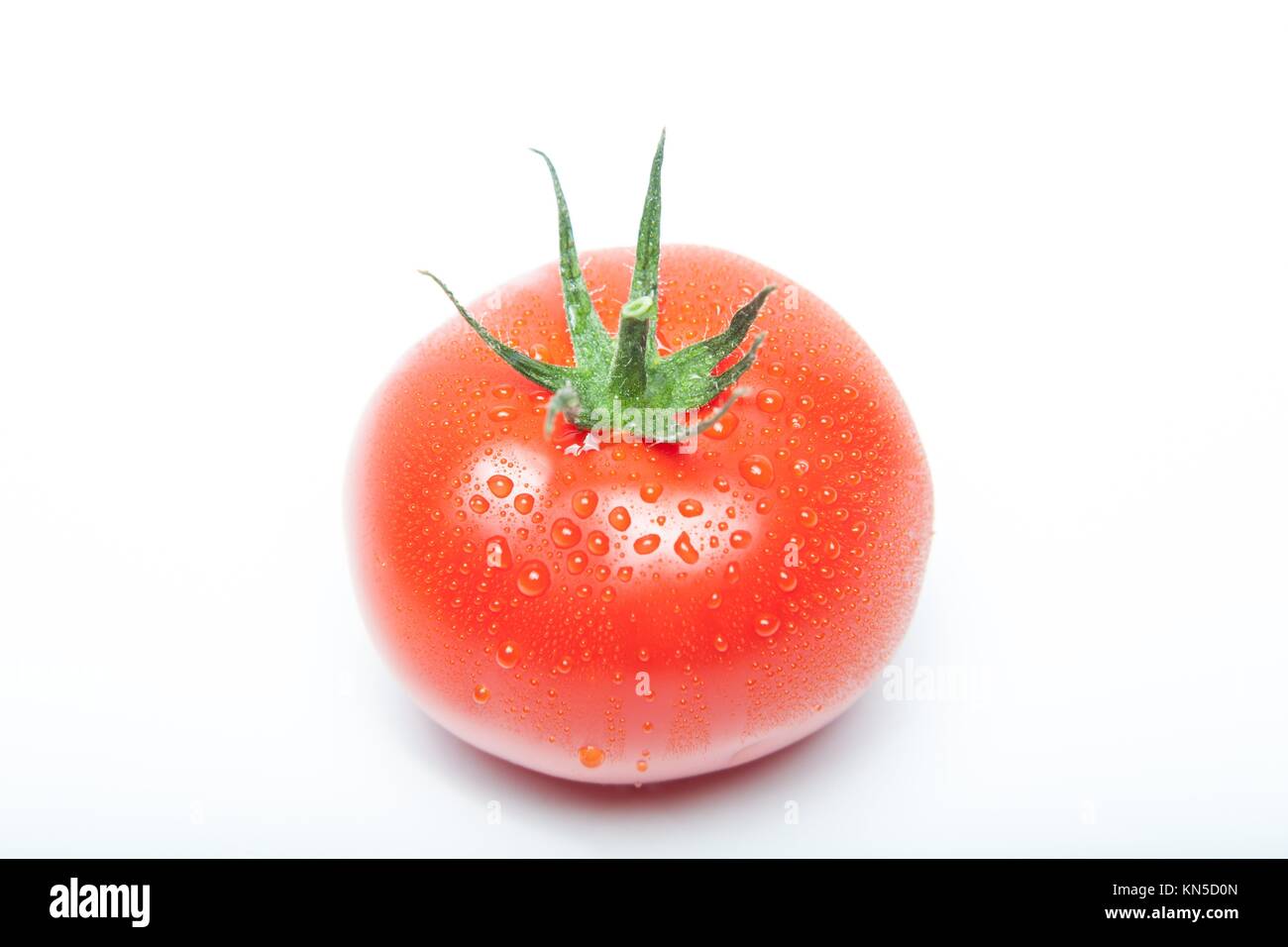 single tomato with water drops on white. Stock Photo