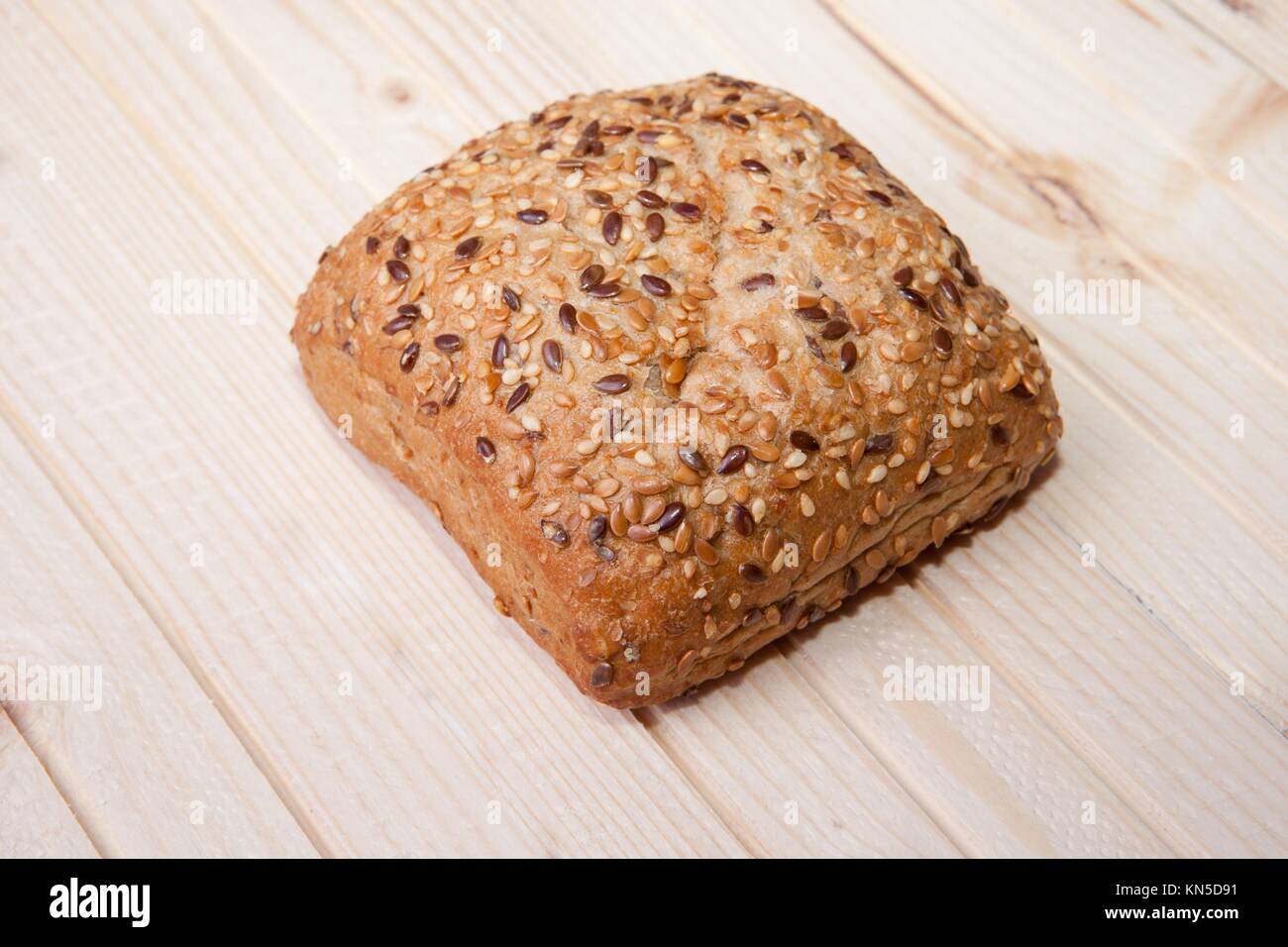 Fresh, squared wholemeal bread with sunflower seeds, sesame and others grains. Isolated over light wooden surface. Stock Photo