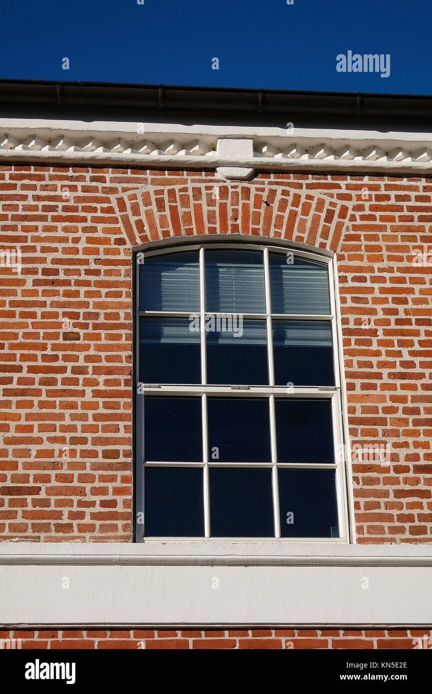 Modernised arched metal window with aluminum blinds in a red brick facade Stock Photo