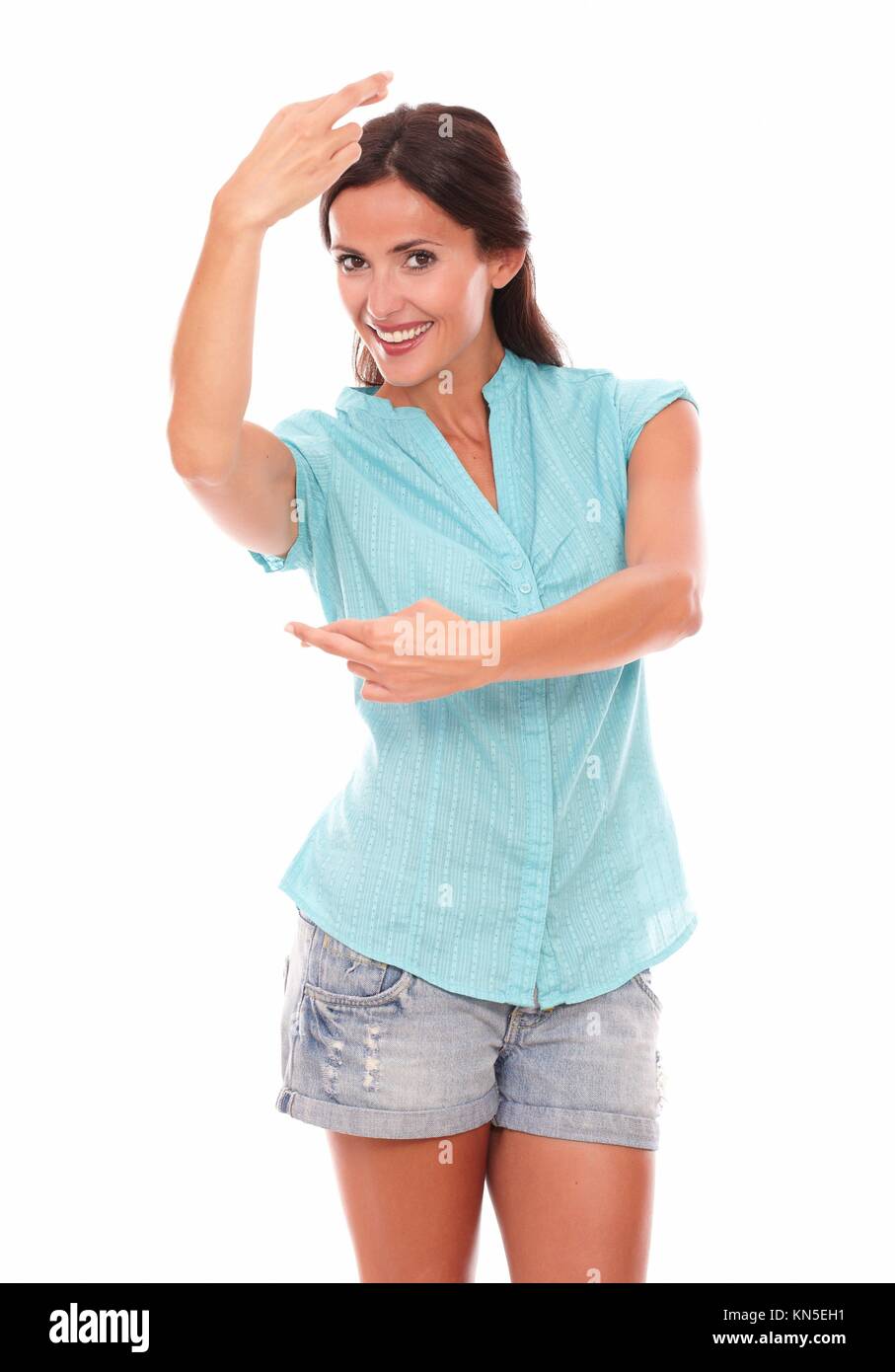 Charming girl making a wish sign while dancing and looking at you in white background. Stock Photo
