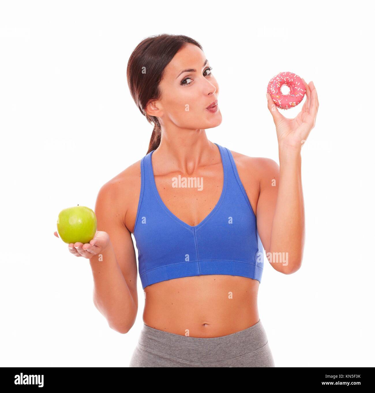 Smiling sporty lady wanting to eat sugary food on isolated background. Stock Photo