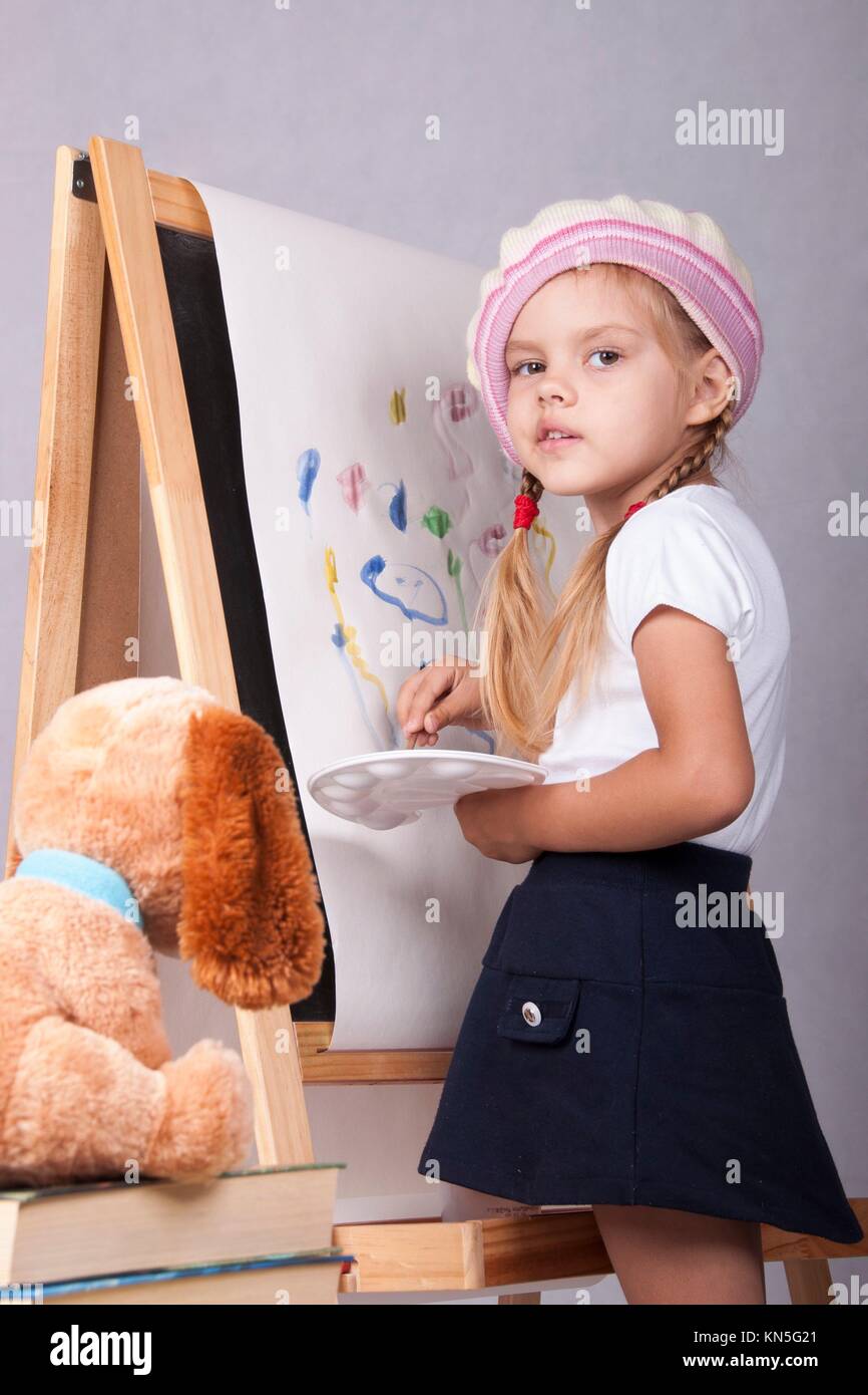 Fouryearold girl playing in the artist and draws on the easel