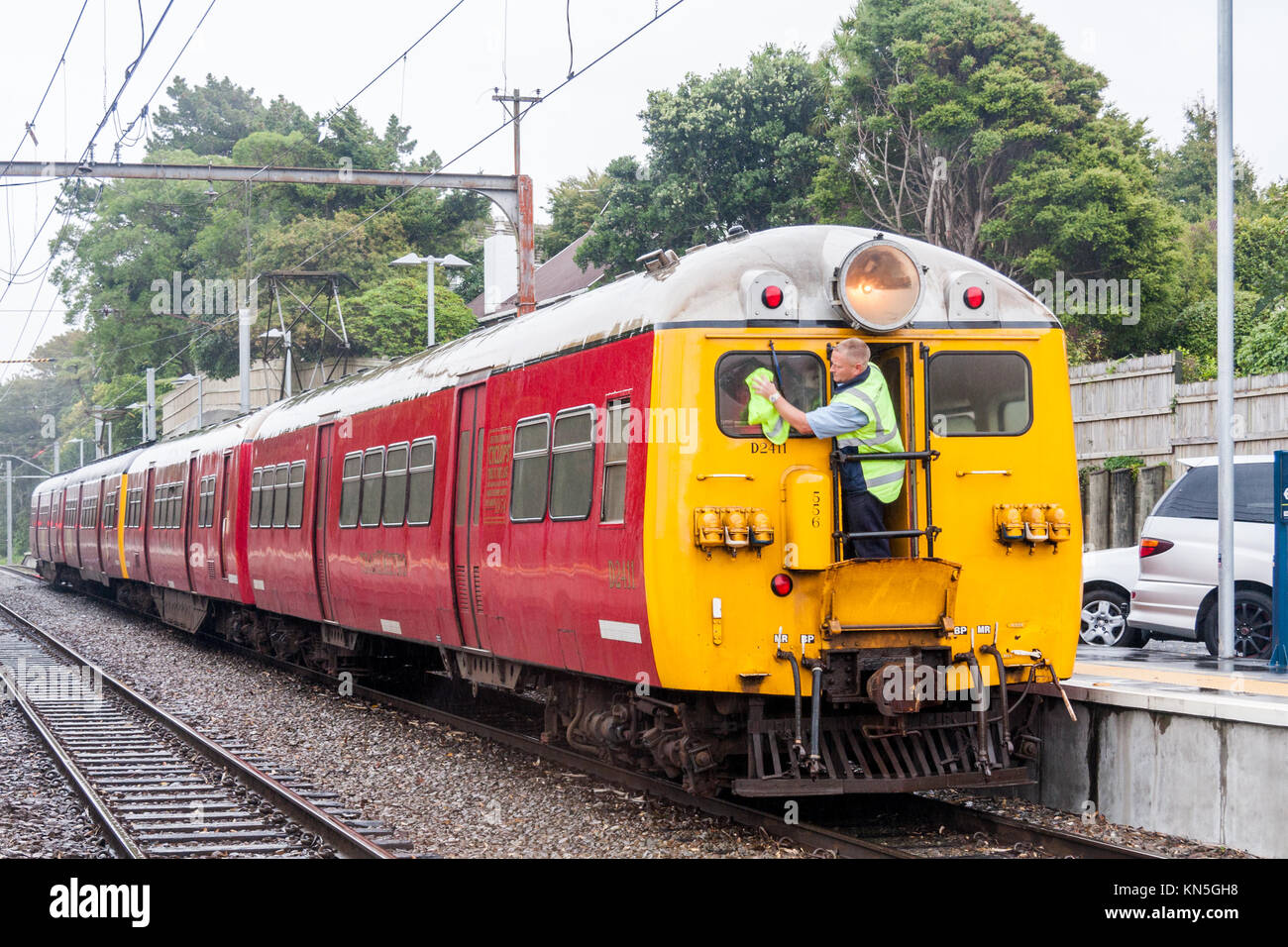 Train driver cleaning windows on Cyclops - the last single headlamp English Electric unit in service since 1954, Wellington, New Zealand Stock Photo