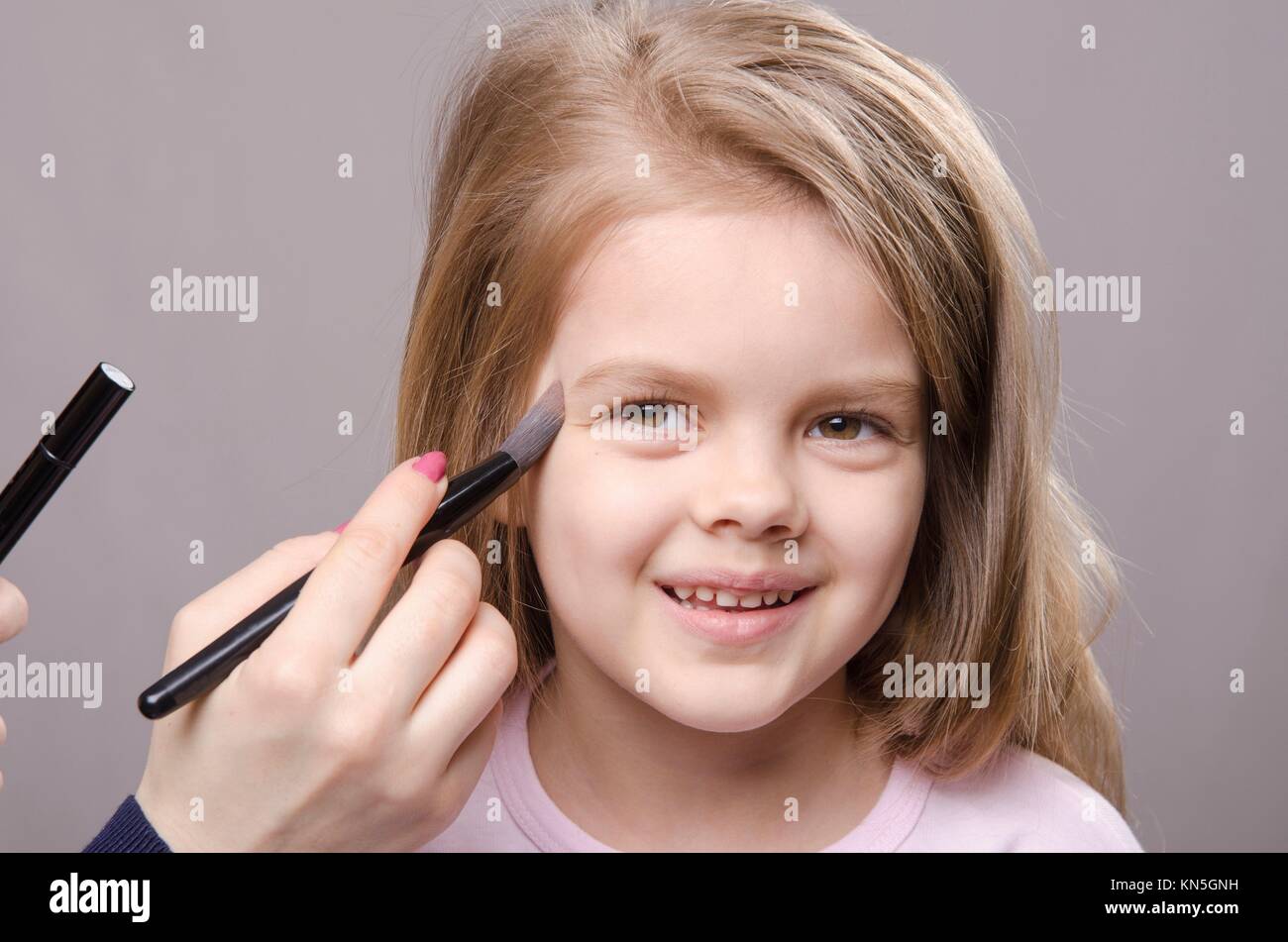 Makeup artist deals powder brush on the face of a five year old girl Stock Photo Alamy