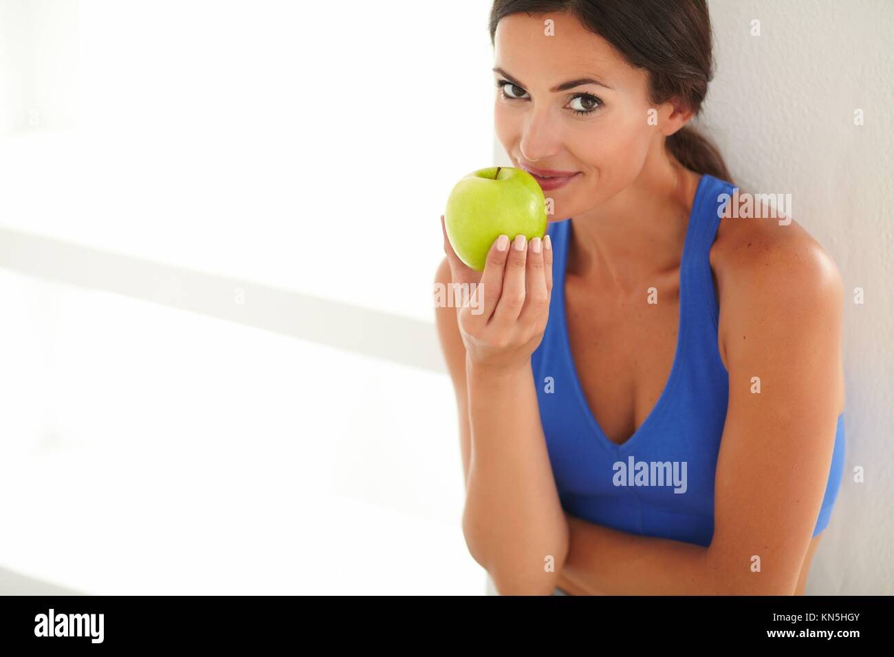 Adult woman in sports clothing holding food and looking at you. Stock Photo
