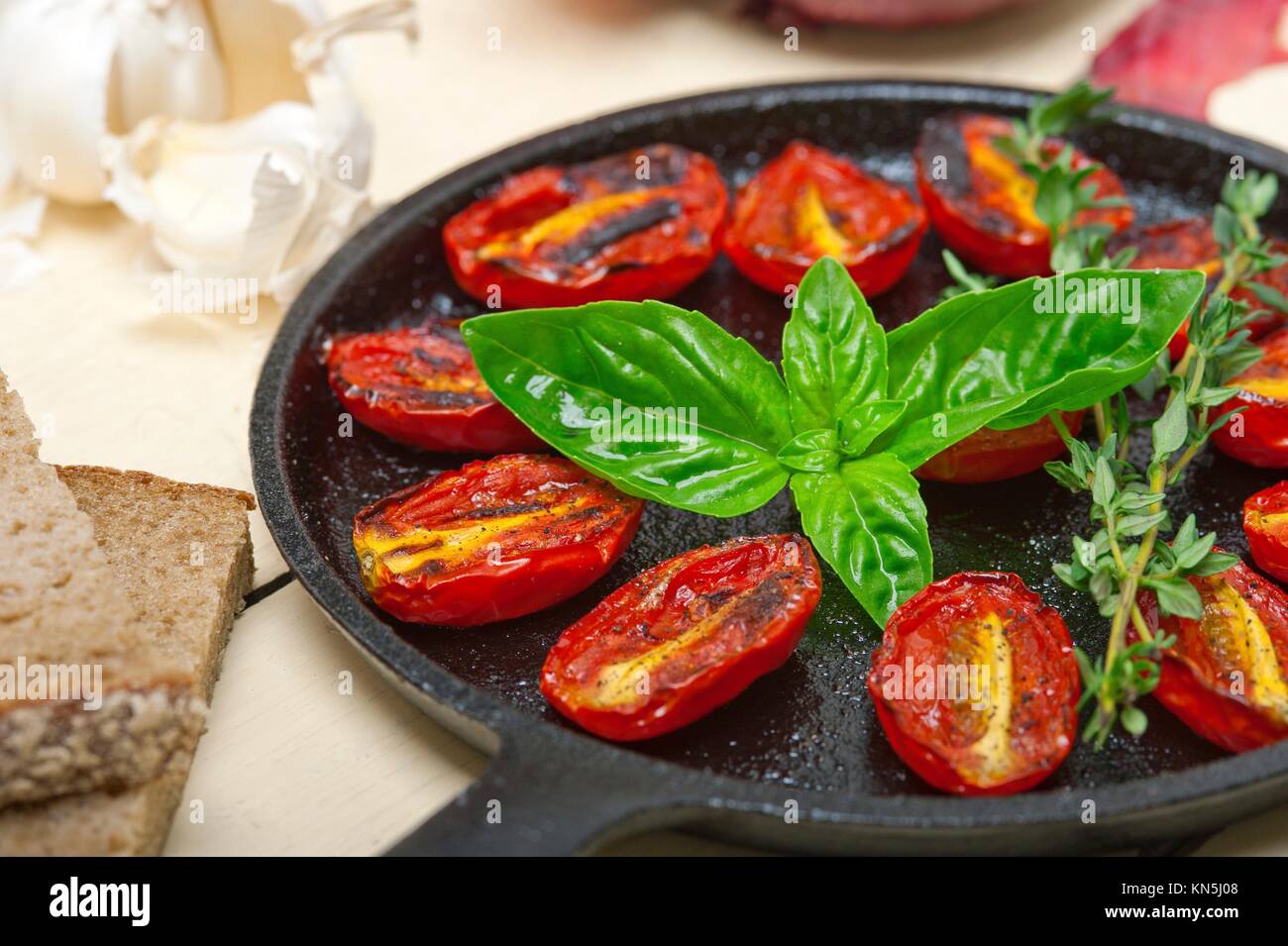 oven baked cherry tomatoes with basil and thyme on a cast iron skillet
