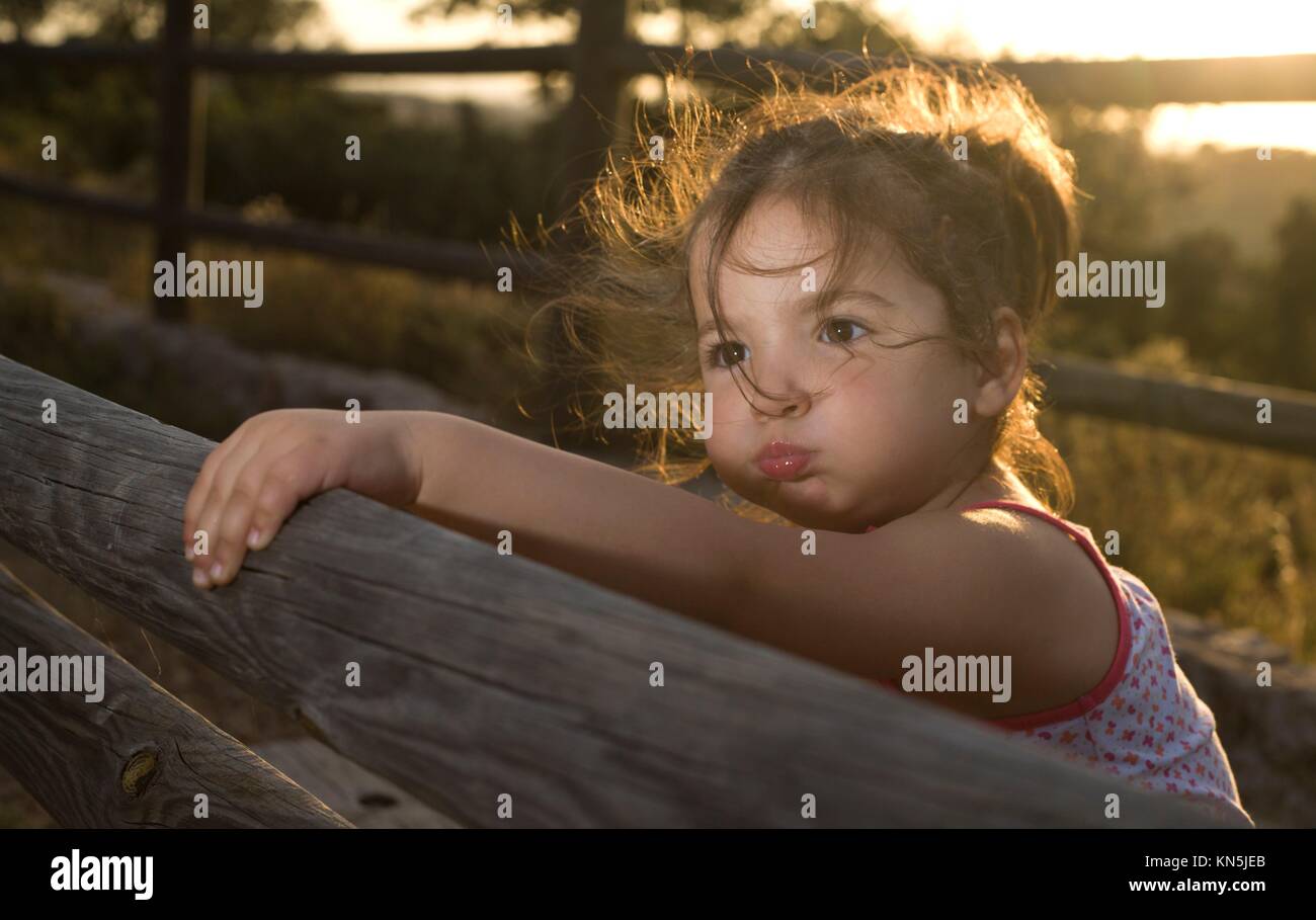 Adorable toddler smiling girl playing in the dehesa field, Extremadura. Magic back light. Sunset. Stock Photo