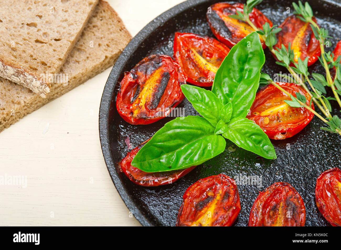 oven baked cherry tomatoes with basil and thyme on a cast iron skillet