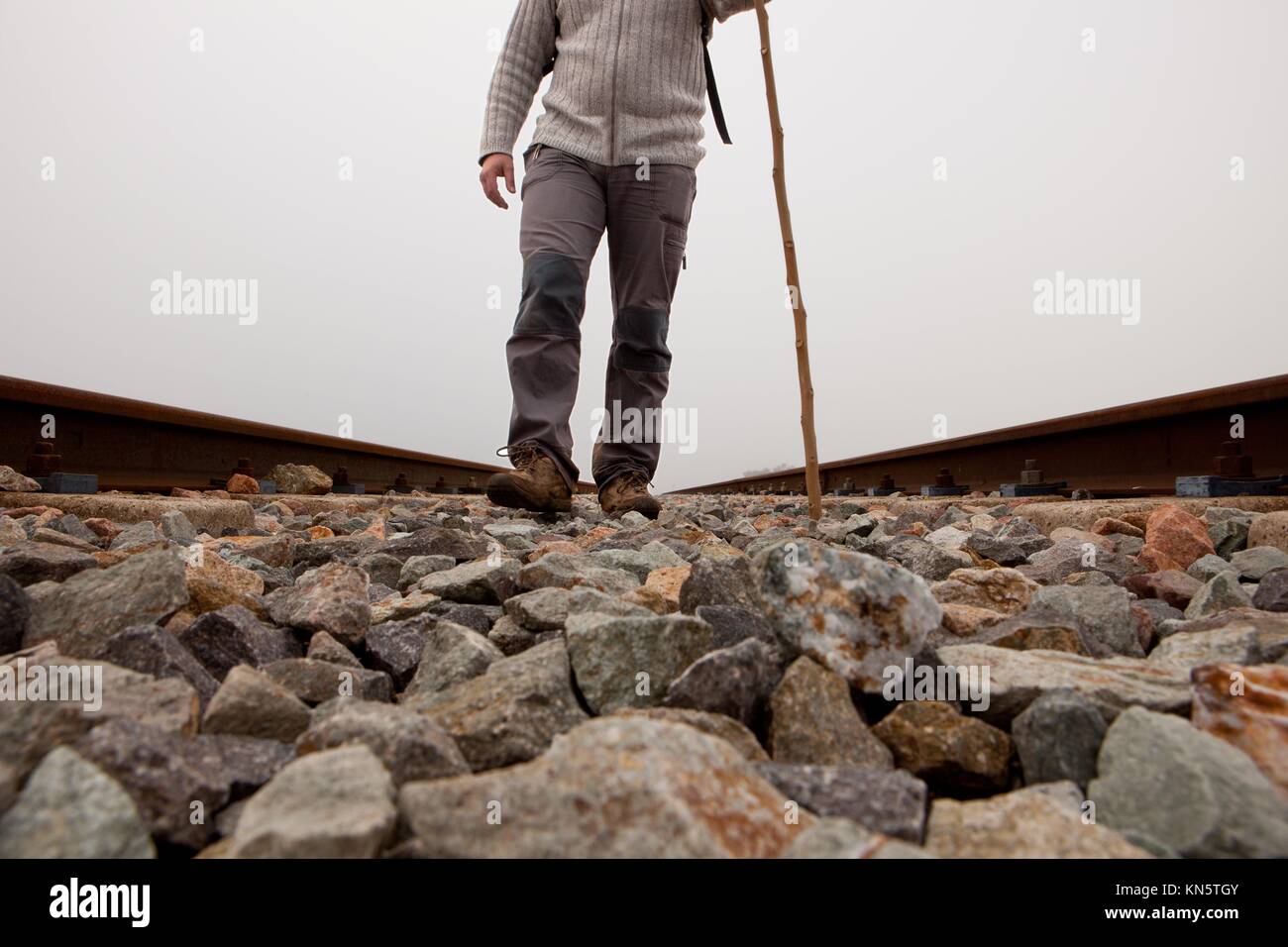 A man walking on the tracks with cane and trekking clothes a dense foggy day. Stock Photo