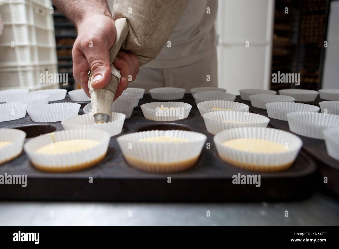Baking cups being piped. Handmade manufacturing process of spanish madeleines. Stock Photo