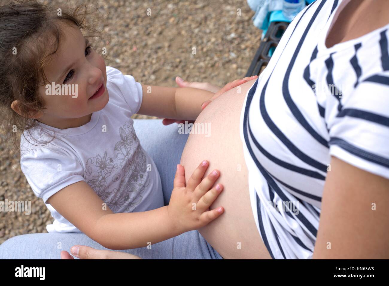 Toddler girl playing with her mother tummy. Stock Photo