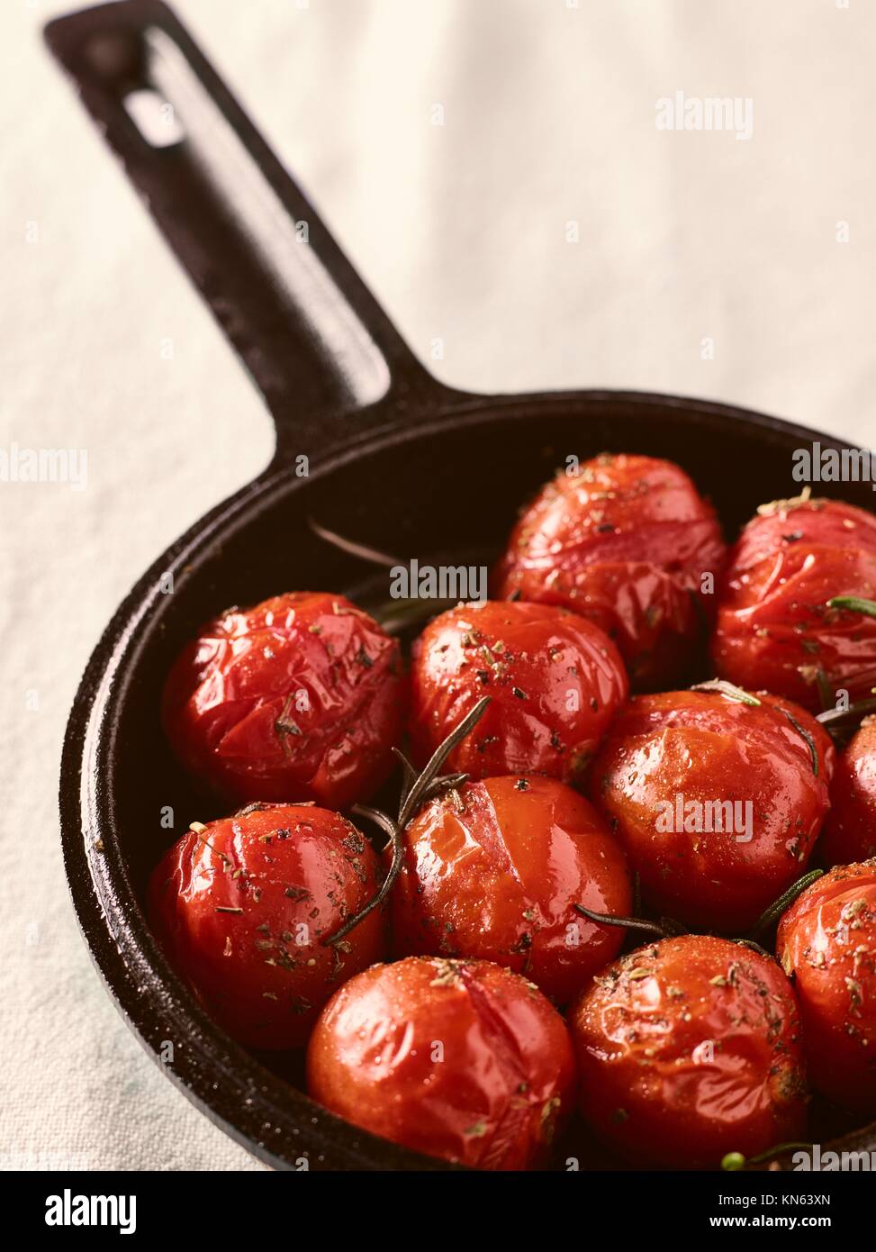 Grilled cherry tomatoes in a small cast iron pot, rosemary, vertical