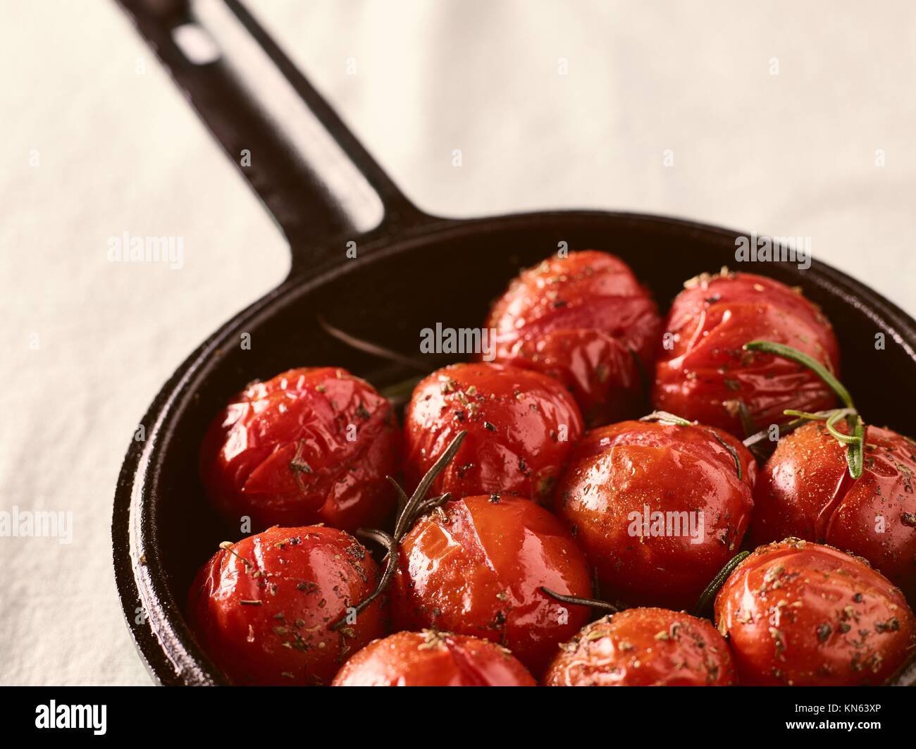 Grilled cherry tomatoes in a small cast iron pot, rosemary, horizon