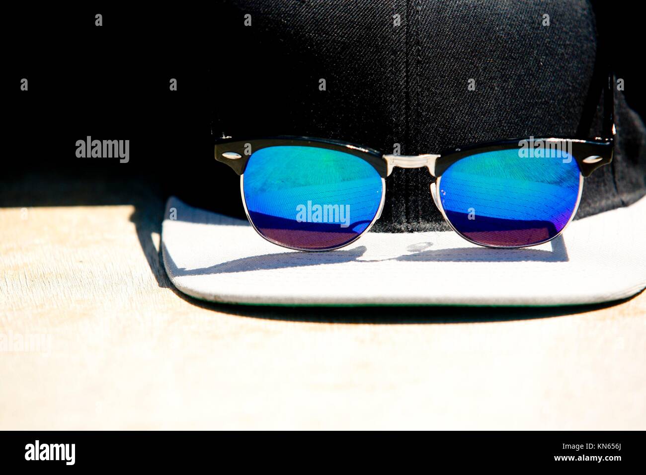 Black cap and blue sunglasses with a reflections. Summer protector for sun. Stock Photo