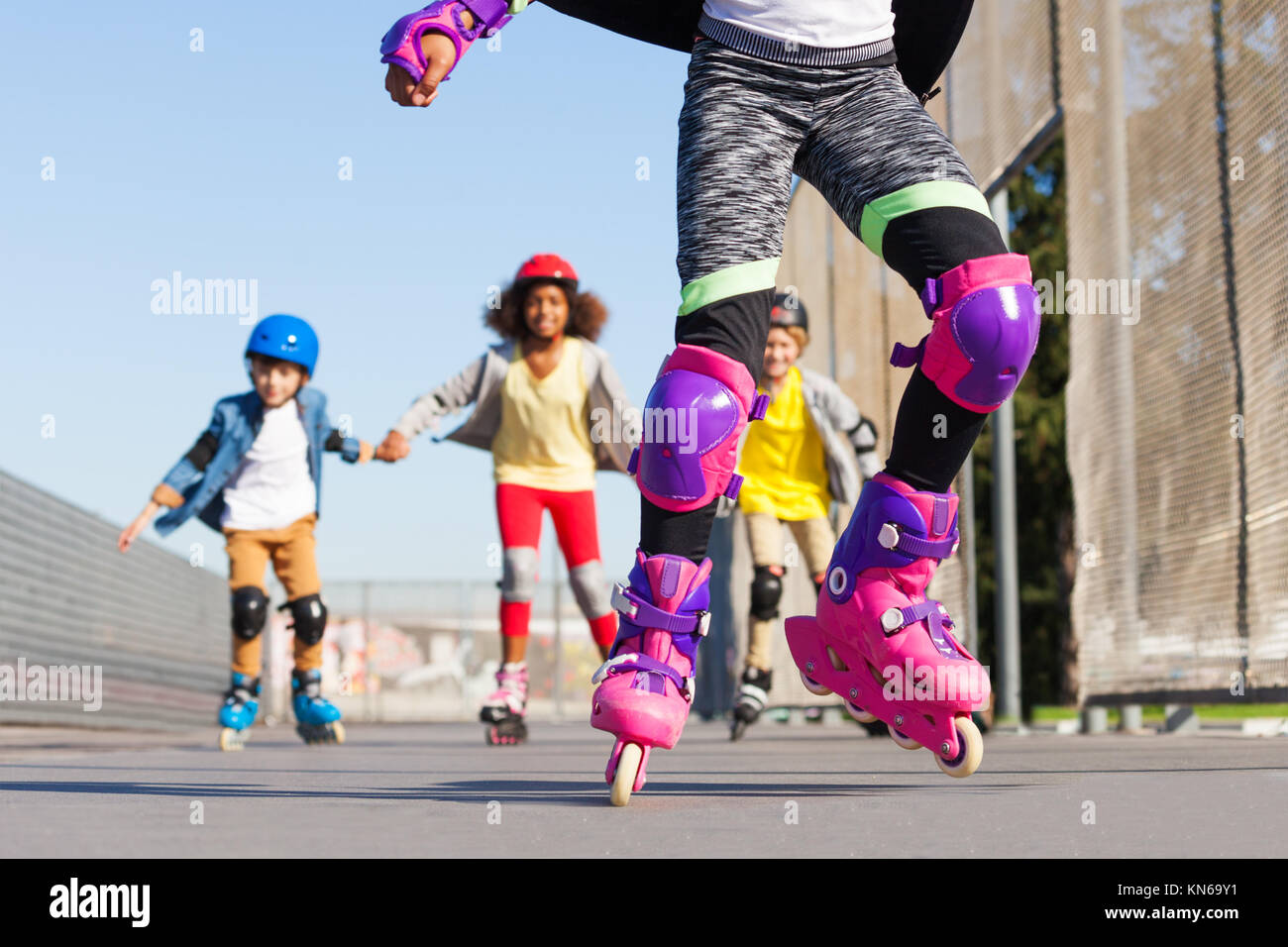 Kids in roller helmets, knee and elbow pads for safe rollerblading