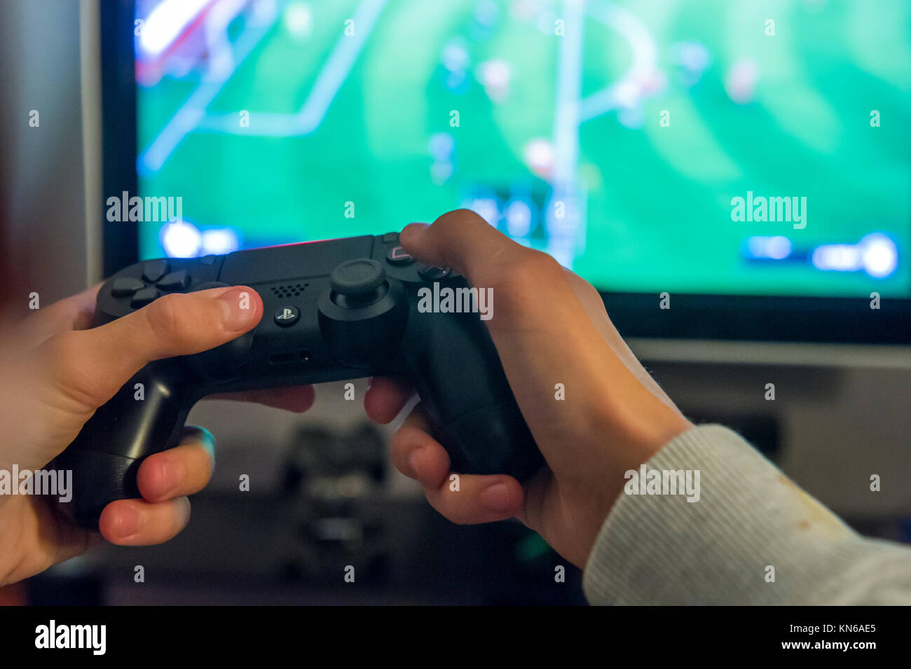 A boy plays a football game on his playstation console Stock Photo