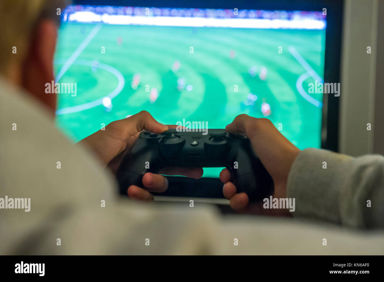 A boy plays a football game on his playstation console Stock Photo