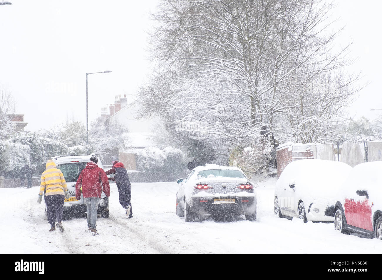 People Help Pushing Stuck Car in Heavy Snow Stock Photo