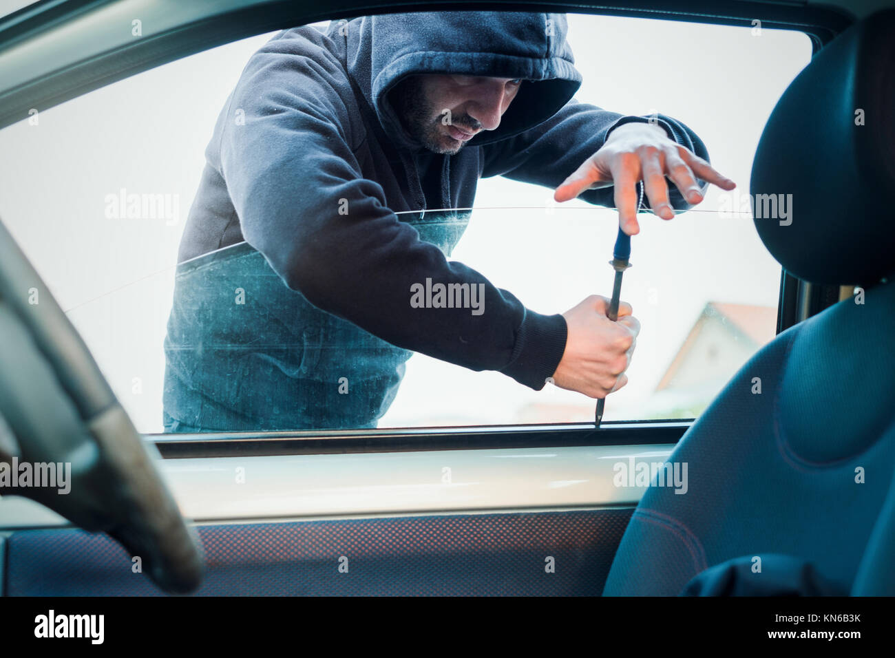 Thief breaking the car window to steal a car Stock Photo Alamy