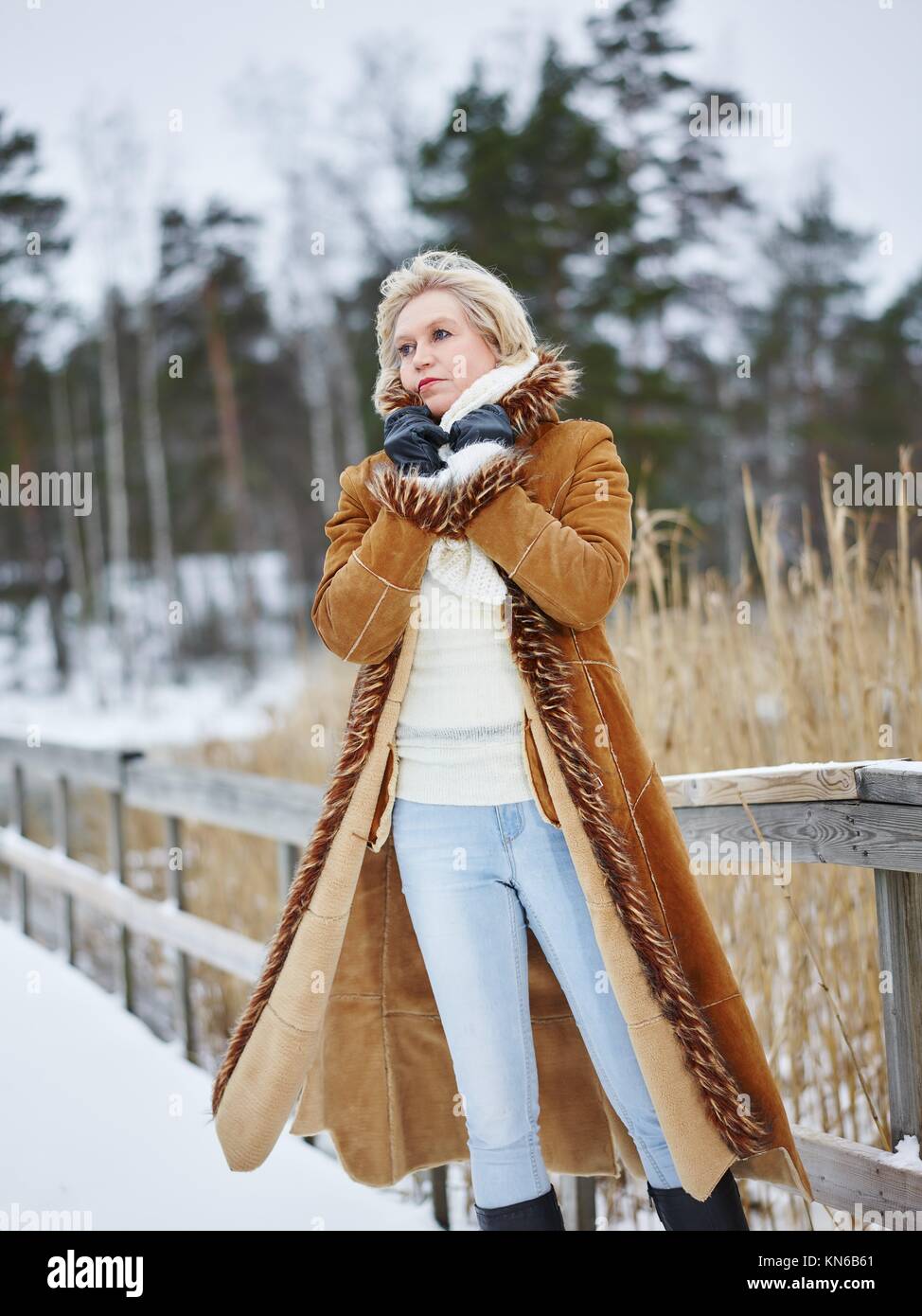 Fashionable mature adult woman wearing winter clothes and she standing next  to the fence - rural scene. South Finland in January Stock Photo - Alamy